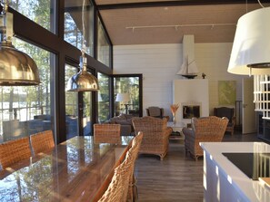 A modern interior with a dining area, wicker furniture, and large windows.