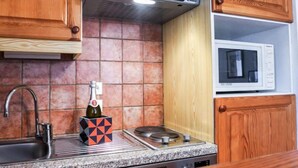 Cozinha com armários de madeira, pia de aço inoxidável, micro-ondas e fogão a gás.