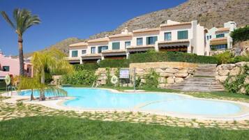 Un hôtel doté d’une piscine, de palmiers et surplombant un paysage montagneux.
