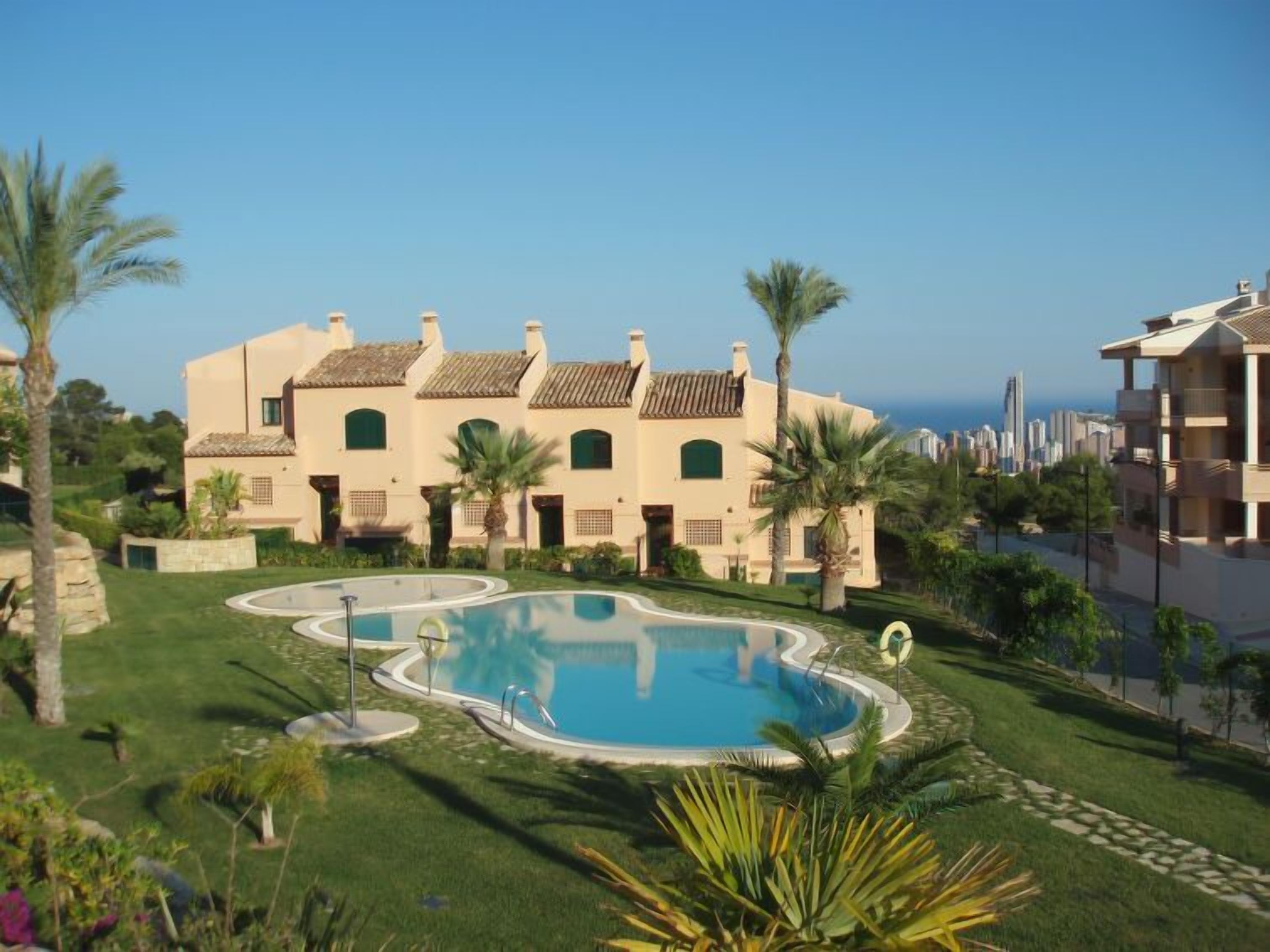 Ein Resort mit Swimmingpool, Palmen und Blick auf den Ozean.