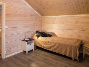 Et lille værelse med en enkeltseng, trævægge og et skråt loft.