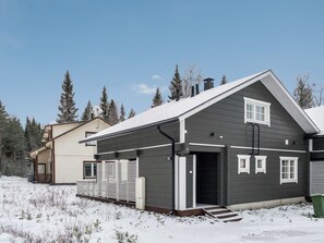 Et tosyltet hus med mørkt ydre, en garage og et sneklædt landskab.
