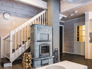 A modern interior with a stone fireplace, wooden staircase, and a clock on the wall. - Leimu a by Interhome (Sotkamo)
