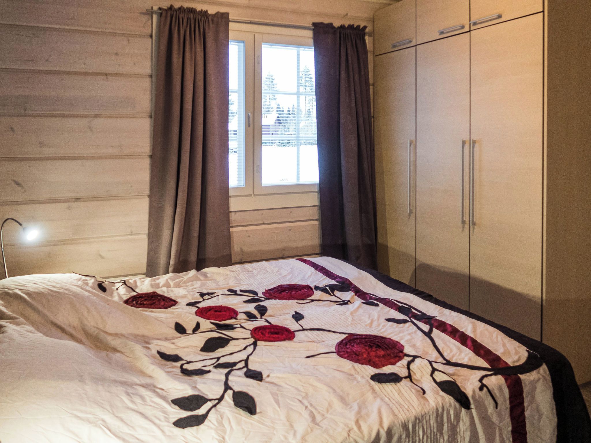 Une chambre à coucher avec un lit, une fenêtre avec des rideaux et une armoire.