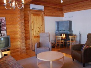 A cozy log cabin interior with a fireplace, wooden walls, a television, and comfortable seating. - Villiruusu by Interhome (Sonkajärvi)