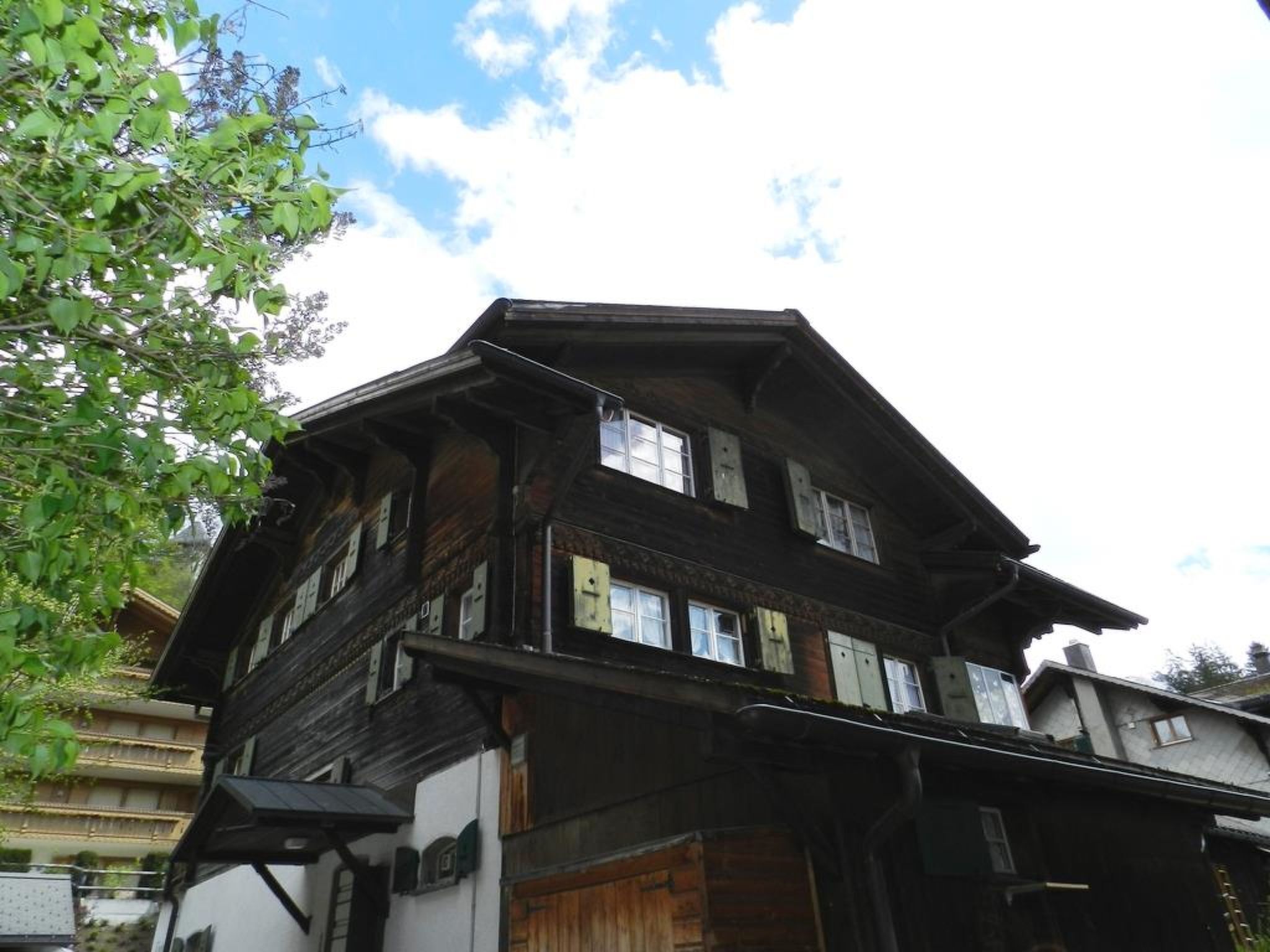 Ein traditionelles, mehrstöckiges Holzhaus mit sichtbaren Fenstern und einem Balkon.