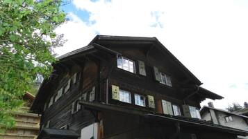 Ein traditionelles, mehrstöckiges Holzhaus mit sichtbaren Fenstern und einem Balkon.