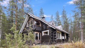 A log cabin with a sloped roof, large windows, and a porch.