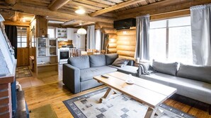 A cozy log cabin interior with a living area, kitchen, and dining space.