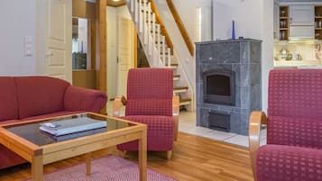 A living room with a red sofa, a glass coffee table, and a fireplace.