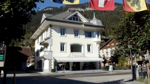 A two-story building with a white facade and a balcony. - Haus am Bach by Interhome (Zweisimmen)