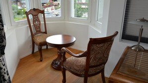 A corner room with a bay window, a round wooden table, two chairs, and a piano. - Haus am Bach by Interhome (Zweisimmen)