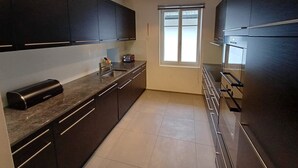 A modern kitchen with dark cabinets, a stainless steel sink, and a window with blinds. - Haus am Bach by Interhome (Zweisimmen)