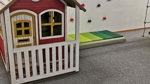 A playhouse with a red roof and white trim, a small porch, and a climbing wall with colorful holds. - Ferienhaus Adonis by Interhome (Saas-Grund)