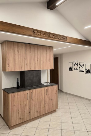 Kitchen features a wooden cabinetry design and black countertop, with a decorative beam above.
