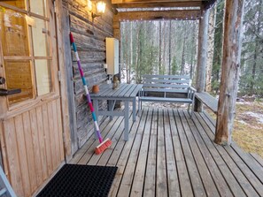 Eine Holz-Blockhütte mit Veranda, einer Bank, einem Tisch und einem an der Wand angelehnten Besen.