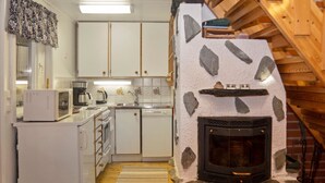 A compact kitchen with white cabinets, a microwave, a coffee maker, and a stone fireplace. - Vacation home Varsta by Interhome (Kuusamo)