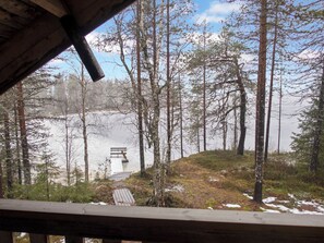 A wooden deck overlooking a forested area with a bench and a small bridge.