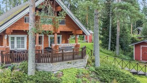 Une cabane en bois dotée d’un porche, entourée d’une forêt dense.