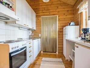Une cuisine de taille réduite, avec des meubles blancs, une cuisinière et un réfrigérateur.