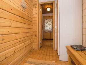 Un couloir intérieur aux murs en bois, avec un banc et une porte donnant sur une autre pièce.