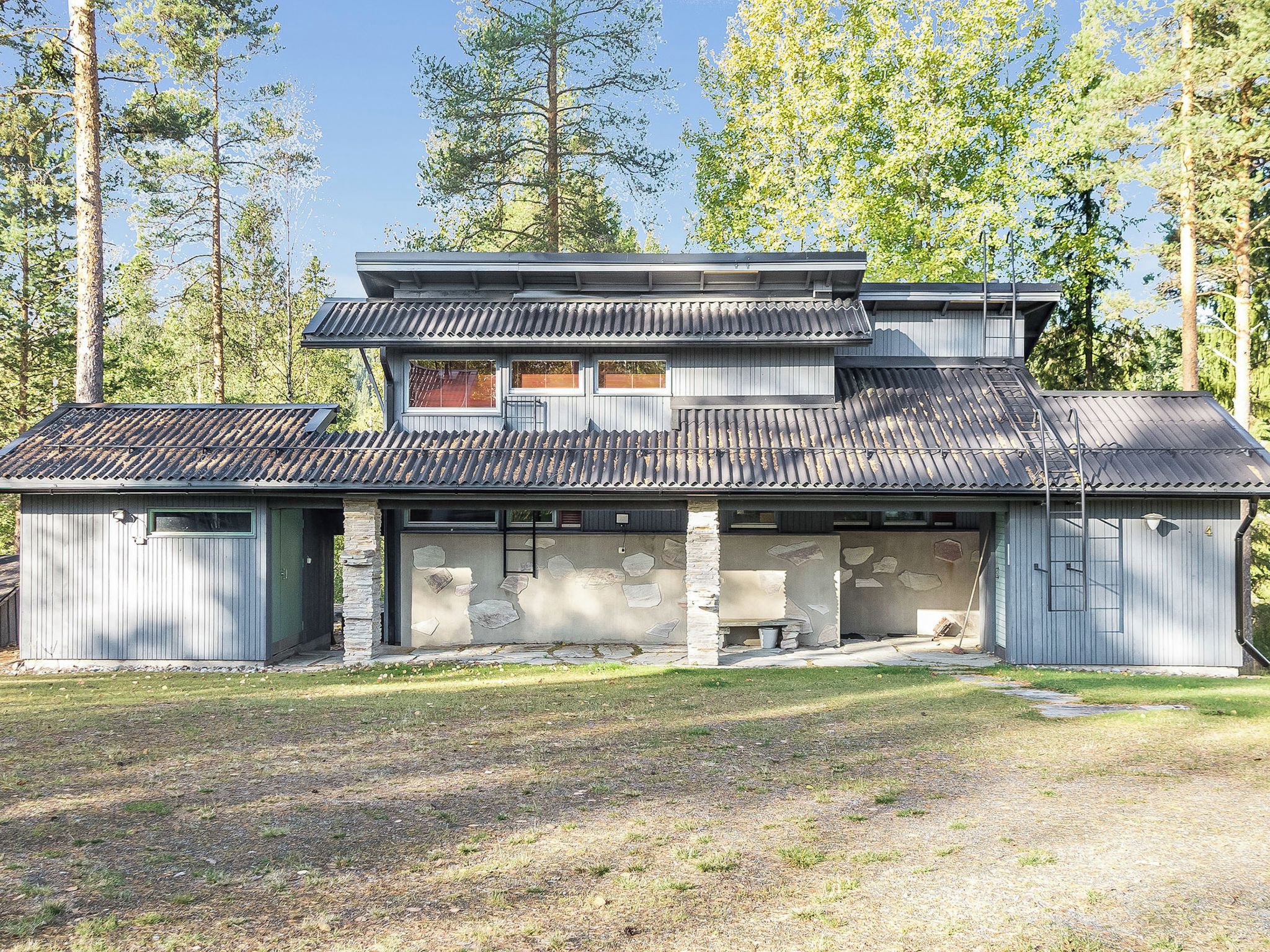 A two-story building with a sloped roof, stone foundation, and a garage.