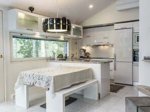 A modern kitchen with a central island, a dining table, and a large window.