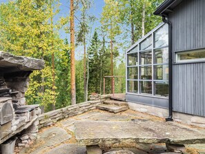 A stone fireplace, a stone bench, and a building with large windows.
