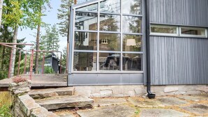 A modern building with large windows and a stone staircase leading to a wooden deck.