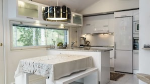 A modern kitchen with a central island, a built-in bench, and a large window providing a view of trees.