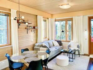 A cozy living room with a sofa, chairs, a coffee table, and a dining table.