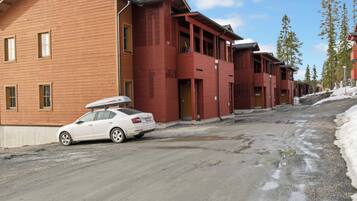 A row of wooden buildings with a car parked in front.