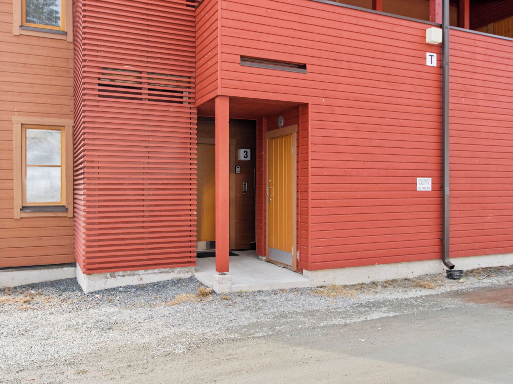 A building with a red exterior, a numbered entrance door, and a small window.