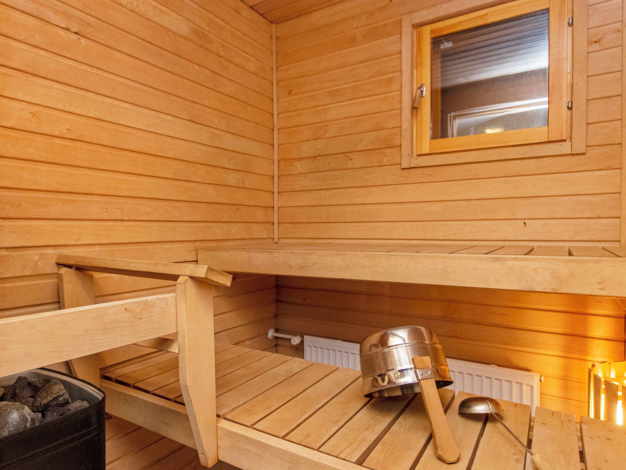 A wooden sauna with a bench, a window, and a sauna head.