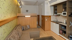 A compact living space with a sofa, a small kitchen area, and a microwave. - Snowflake b 24 by Interhome (Kuusamo)