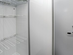 Un vestidor con estanterías metálicas y una puerta con pomo.