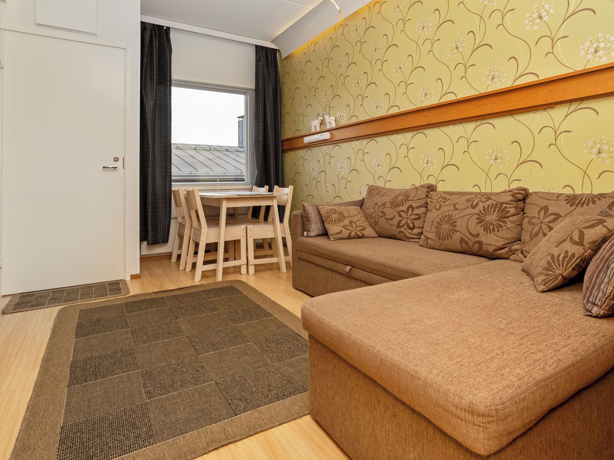 Una sala acogedora con un sofá, una mesa de comedor con sillas y una pared con diseño.