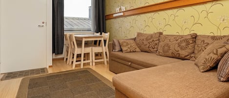 Uma sala de estar acolhedora com um sofá, uma mesa de jantar com cadeiras e um papel de parede estampado.