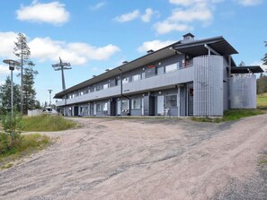 A multi-story building with a flat roof and a gravel driveway.