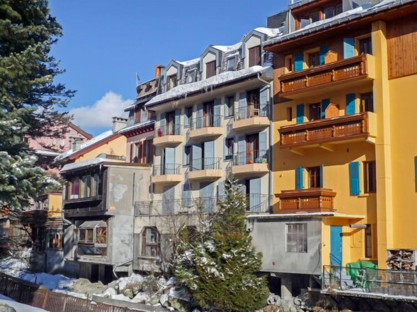 Un hôtel à plusieurs étages, doté de balcons et d’un toit enneigé.