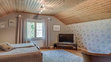 Un dormitorio con dos camas, televisión y una ventana con cortinas.