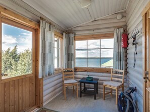 Una cabaña con interior de madera, una mesa, dos sillas y vistas al agua.