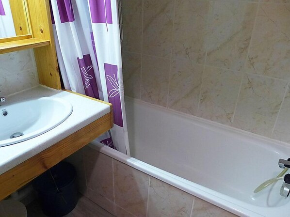 Une salle de bain équipée d’un lavabo, d’une baignoire et d’un rideau de douche.