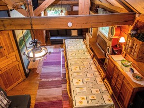 A cozy cabin interior with a wooden ceiling, a bed with floral bedding, a dining table, and a window with curtains. - Kuusenkatve by Interhome (Nilsiä)