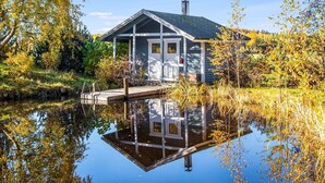 A houseboat with a dock, surrounded by autumn foliage and a calm body of water. - Kuusenkatve by Interhome (Nilsiä)