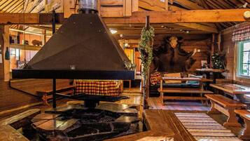 A rustic interior with a wood-burning stove, wooden furniture, and a stone fireplace.