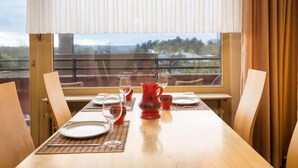 A dining table set with plates, glasses, and a red pitcher, with a view of a balcony and landscape through a window. - Birke (A504) by Interhome (Lahnstein (Koblenz))