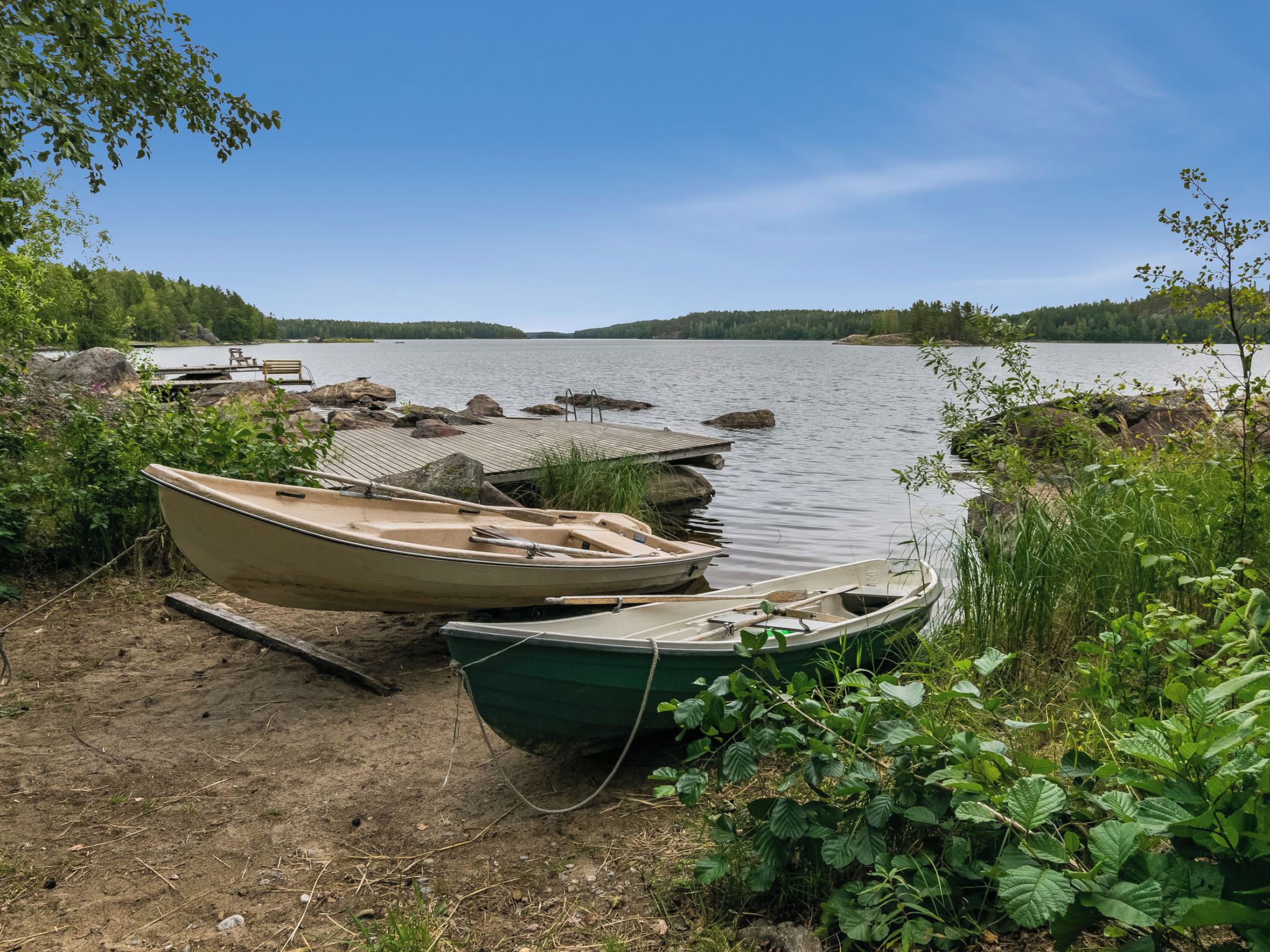 Um cais à beira do lago com várias embarcações atracadas, cercado por vegetação e um céu claro.