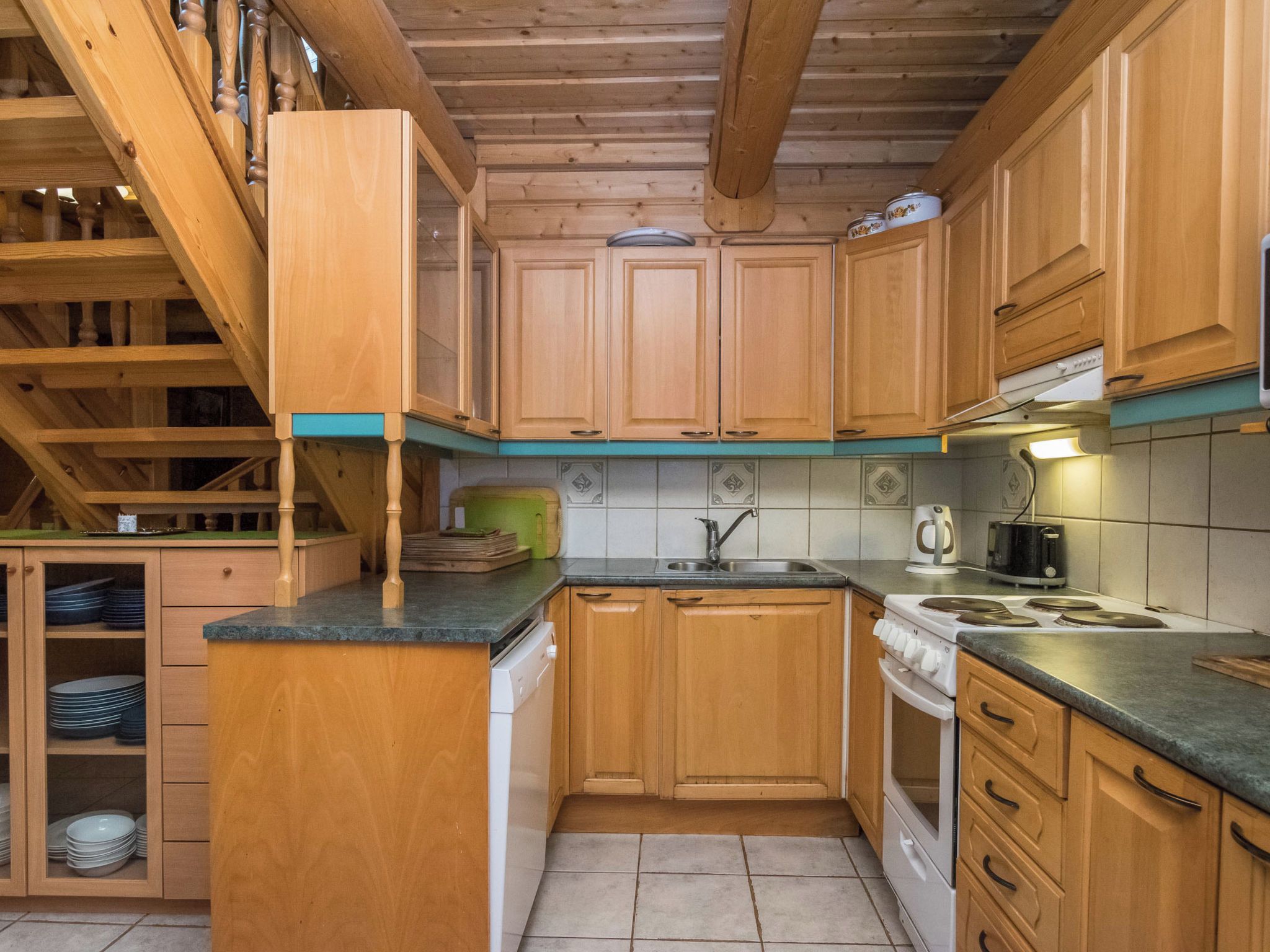 Une cuisine avec des meubles de rangement en bois, une cuisinière et un évier.