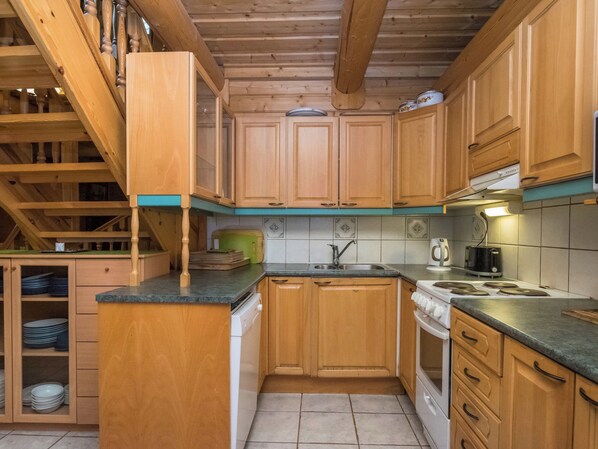 A kitchen with wooden cabinets, a stove, and a sink.